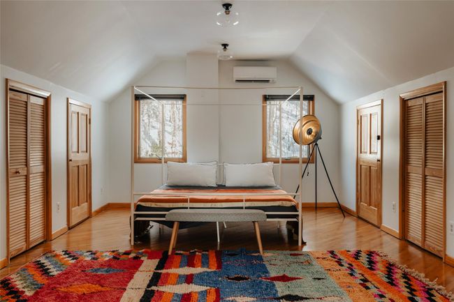 Bedroom featuring storage closets, vaulted ceiling, a wall unit AC, and light wood-type flooring | Image 21