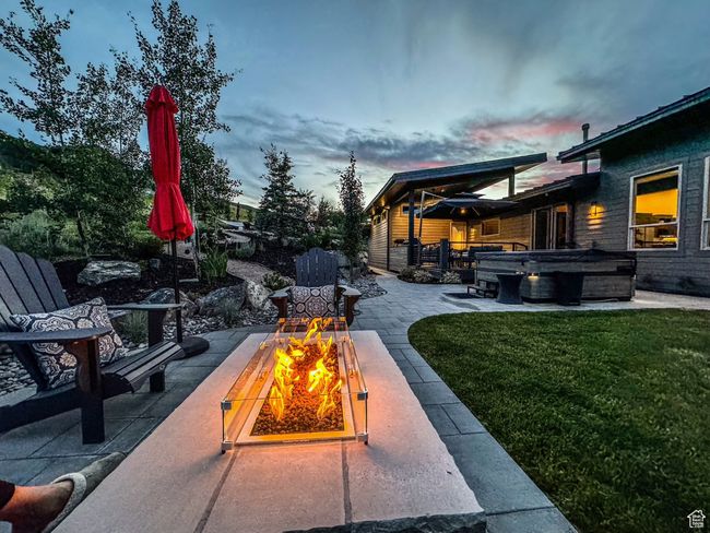 Patio terrace at dusk featuring a hot tub, a fire pit, a patio area, and a lawn | Image 75