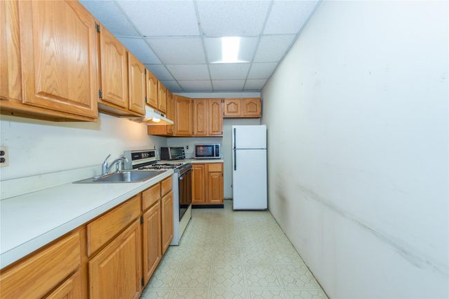 Kitchen featuring a sink, light countertops, freestanding refrigerator, stainless steel microwave, and gas stove | Image 34