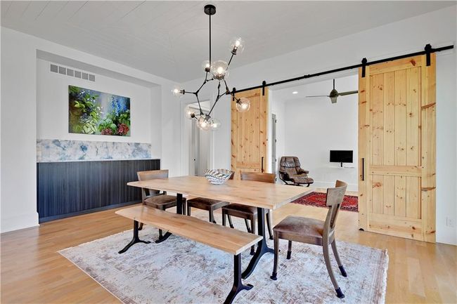 Dining area with light wood finished floors, visible vents, an inviting chandelier, and a barn door | Image 26
