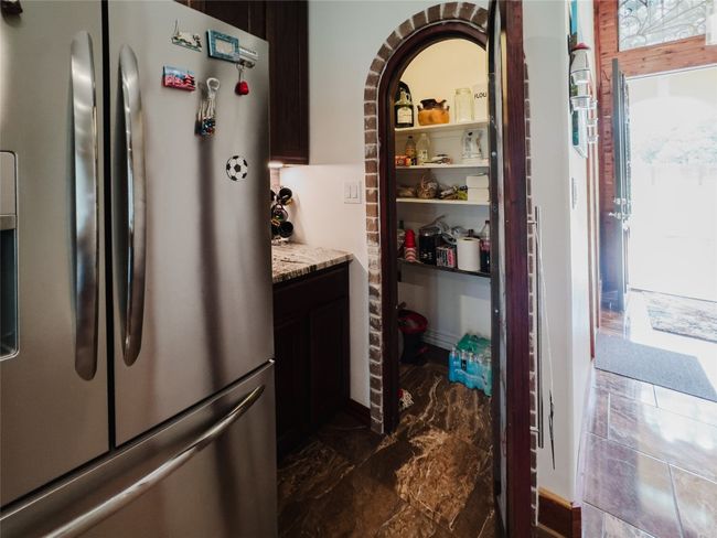 Kitchen with freestanding refrigerator, light stone countertops, and dark marble finish floors | Image 25