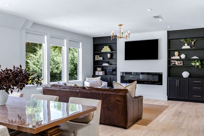 Living room featuring a chandelier, light wood finished floors, built in features, recessed lighting, and a glass covered fireplace | Image 13