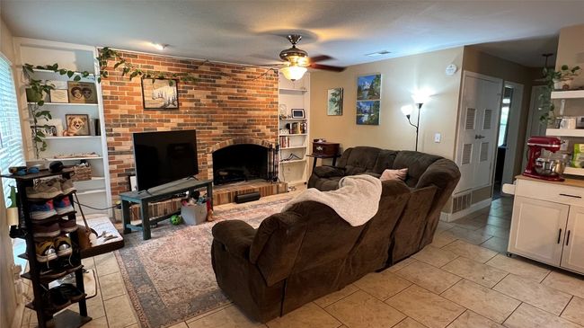 Living area featuring ceiling fan, a fireplace, and light tile patterned floors | Image 13