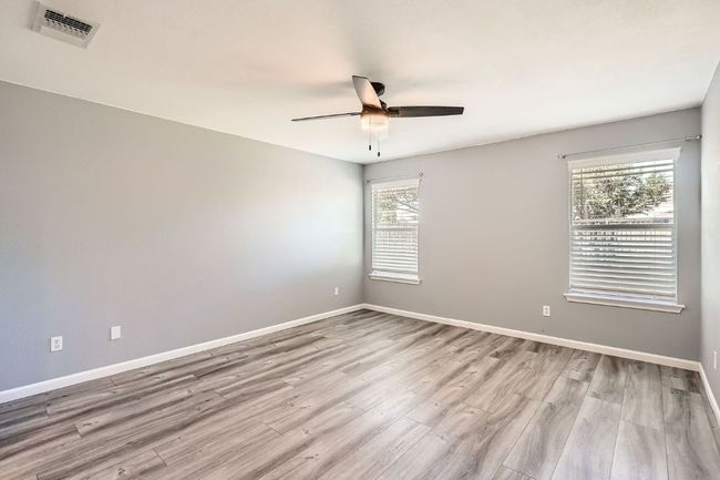 Empty room with baseboards, ceiling fan, visible vents, and wood finished floors | Image 12