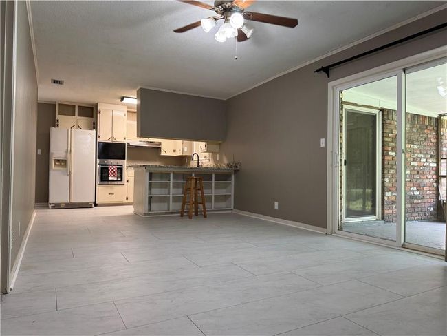 Unfurnished living room featuring ceiling fan and crown molding | Image 6