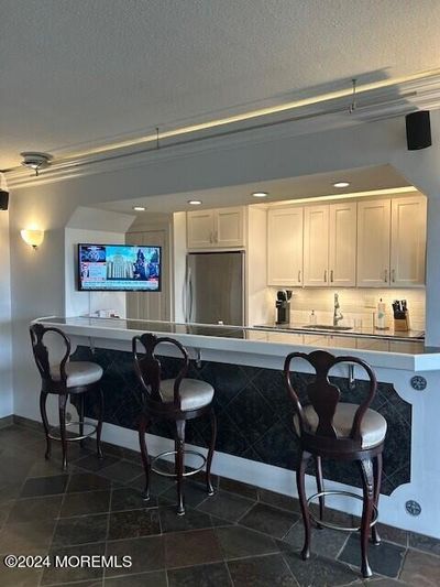 The 10+ foot long bar opens to a completely renovated kitchen for ideal entertaining. Slate flooring is throughout the apartment. | Image 2