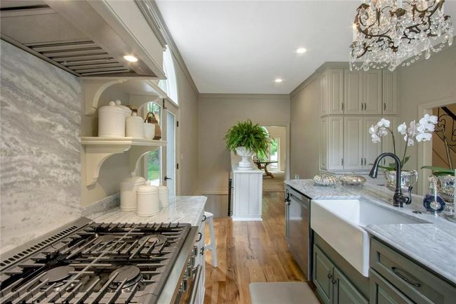 Kitchen featuring light stone countertops, dishwasher, light wood-type flooring, premium range hood, and sink | Image 17