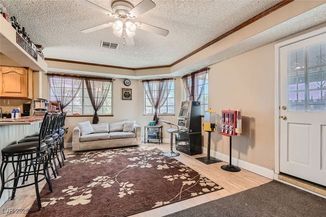 Living room with visible vents, ornamental molding, light wood-style floors, ceiling fan, and a textured ceiling | Image 15