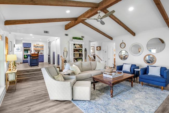 Living room with visible vents, light wood-type flooring, a ceiling fan, and vaulted ceiling with beams | Image 8