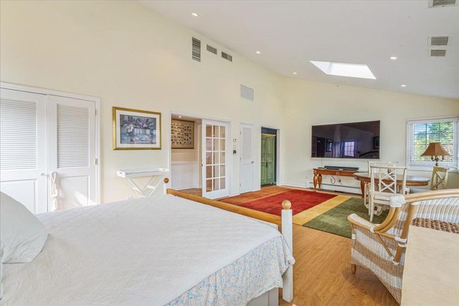 Bedroom featuring high vaulted ceiling, a skylight, a baseboard heating unit, wood finished floors, and recessed lighting | Image 18