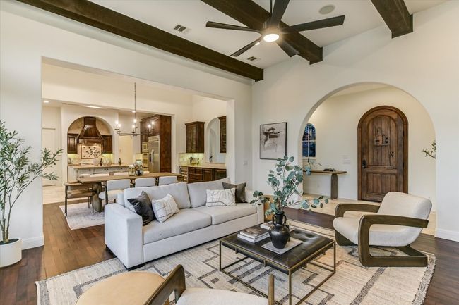Open floor plan concept. Living area featuring, wood beamed ceiling, and mesquite hardwood flooring, with fireplace and built in cabinetry | Image 11