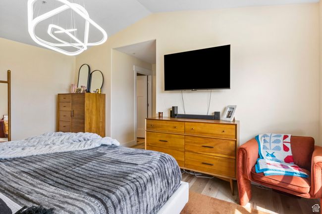Bedroom with light wood-style flooring, a chandelier, and vaulted ceiling | Image 17