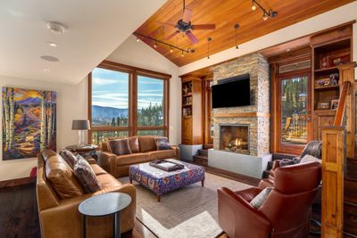 Living room with a stone fireplace, vaulted wood ceiling, hardwood / wood floors | Image 2