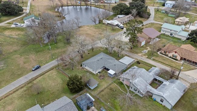This aerial photo showcases the home and there is a small pond surrounded by trees, providing a natural setting. | Image 45