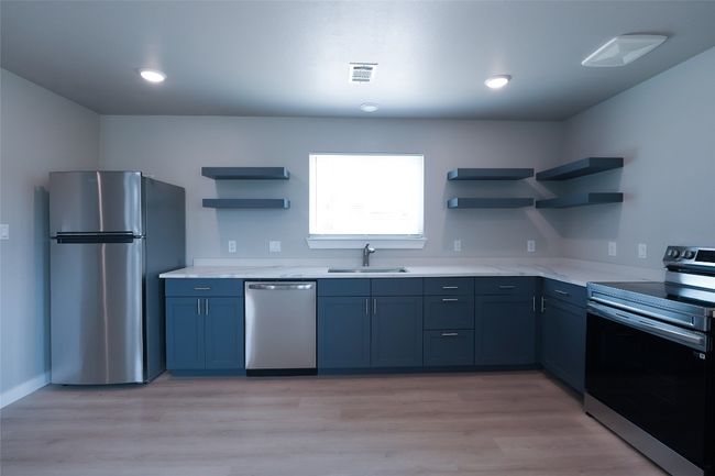 Kitchen featuring stainless steel appliances, open shelves, light wood-style flooring, and blue cabinets | Image 13