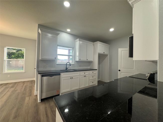 Kitchen featuring dishwasher, dark wood-style flooring, recessed lighting, white cabinets, and backsplash | Image 9