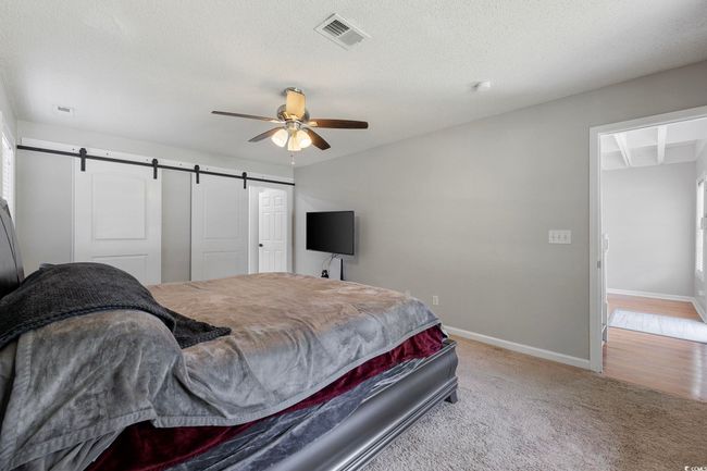 Carpeted bedroom featuring a barn door, baseboards, a ceiling fan, and a textured ceiling | Image 18