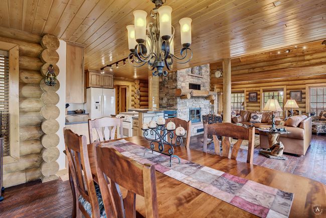 Dining space with log walls, wood ceiling, hardwood / wood-style floors, a chandelier, and a stone fireplace | Image 11
