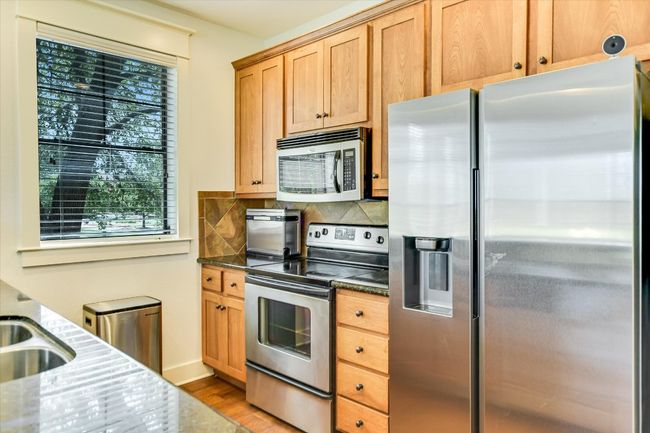 Kitchen with stainless steel appliances, light wood-style flooring, dark stone counters, and tasteful backsplash. | Image 9