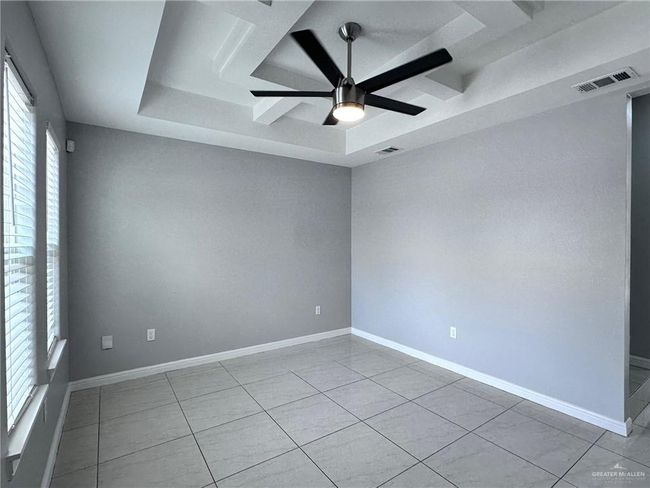 Tiled empty room featuring baseboards, ceiling fan, visible vents, and a raised ceiling | Image 5