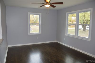 Spare room featuring dark wood-type flooring, ceiling fan, and a healthy amount of sunlight | Image 3