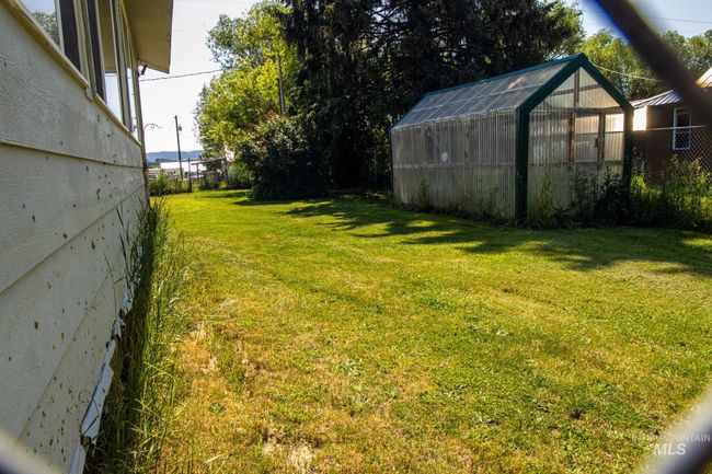 View of yard featuring a greenhouse and an outbuilding | Image 7