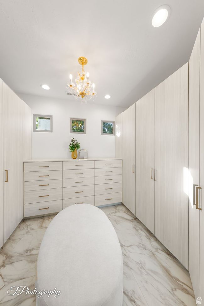 Spacious closet featuring light marble finish floors and a chandelier | Image 47