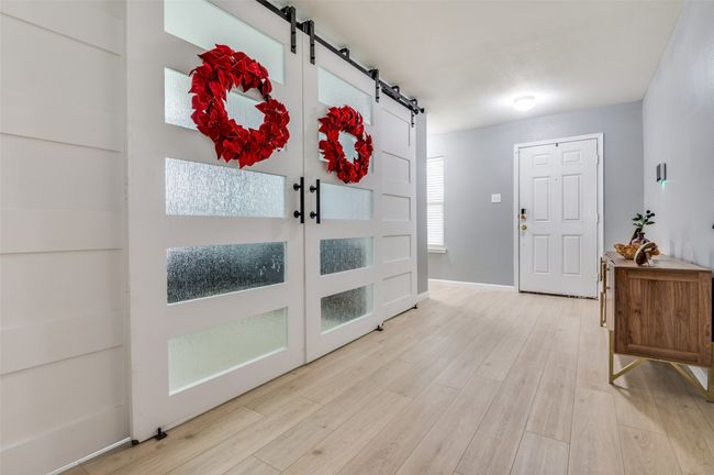 Foyer entrance featuring a barn door and wood finished floors. | Image 15