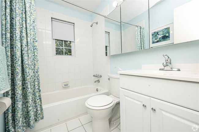 Bathroom featuring shower / bathtub combination with curtain, toilet, vanity, and tile patterned flooring | Image 6
