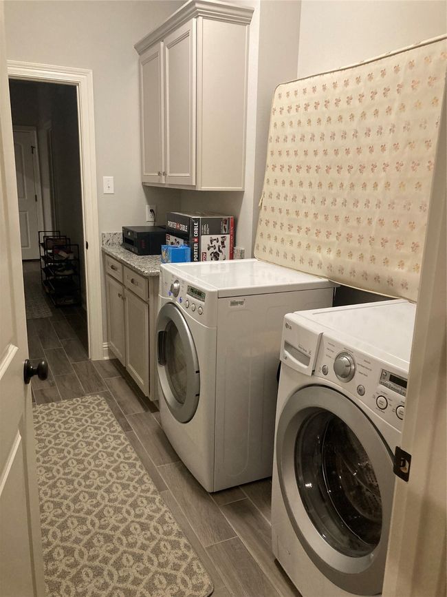 Laundry room with wood tiled floor, cabinet space, and separate washer and dryer | Image 15