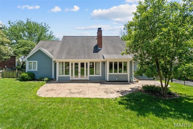 Rear view of property featuring french doors, a patio area, a chimney, and a shingled roof | Image 64