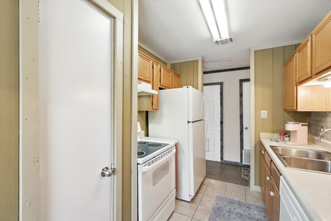 Kitchen with white appliances, light tile patterned floors, light countertops, and under cabinet range hood | Image 7