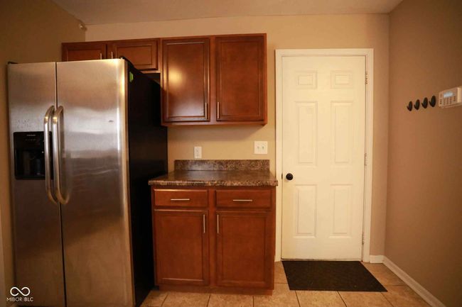 kitchen featuring dark countertops, light tile patterned flooring, baseboards, and stainless steel fridge with ice dispenser | Image 21