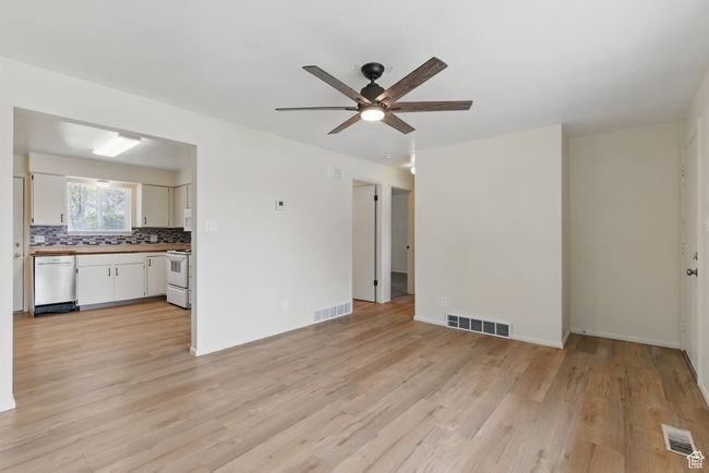 Unfurnished living room featuring light wood-type flooring, visible vents, and ceiling fan | Image 7