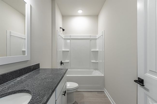 Bathroom featuring vanity, wood finished floors, baseboards, tub / shower combination, and toilet | Image 9