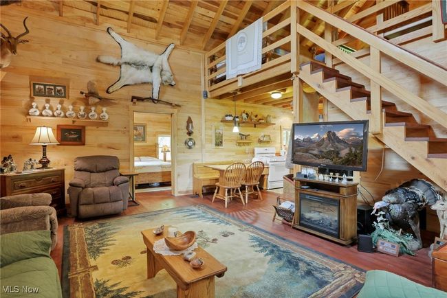 Living area featuring wooden walls, wood finished floors, wood ceiling, and stairway | Image 17