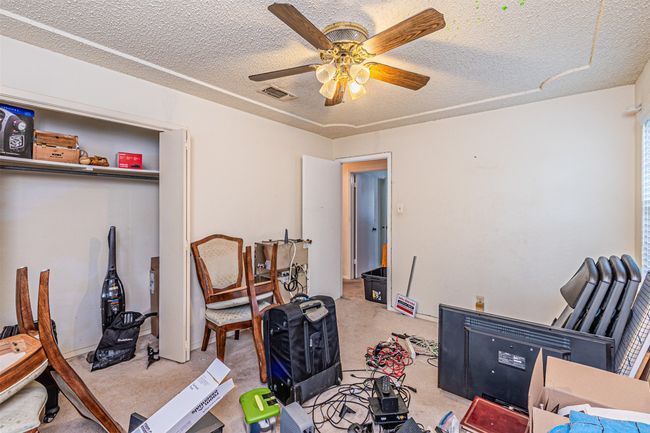Home office featuring a ceiling fan, visible vents, light colored carpet, and a textured ceiling | Image 13