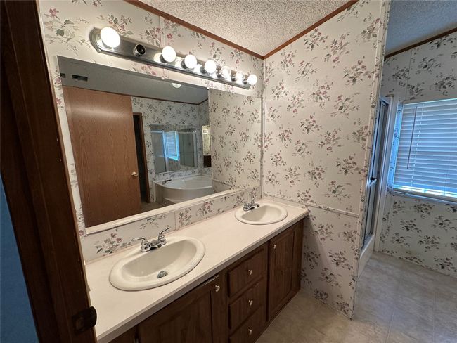 Bathroom with wallpapered walls, ornamental molding, a textured ceiling, a shower stall, and tile patterned floors | Image 20