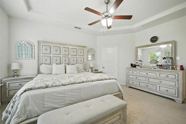 Bedroom with light colored carpet, a tray ceiling, and a ceiling fan | Image 17
