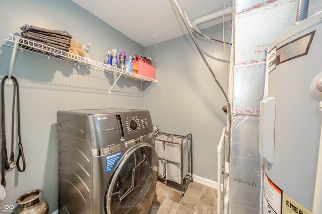 clothes washing area with washer / dryer, stone finish flooring, and baseboards | Image 22