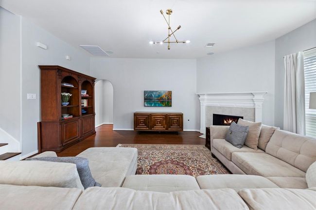 This spacious living room offers a warm and inviting atmosphere, anchored by a classic fireplace and framed by clean architectural lines. | Image 12