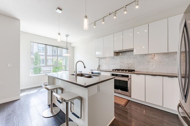 Kitchen with appliances with stainless steel finishes, backsplash, modern cabinets, white cabinets, and under cabinet range hood | Image 11