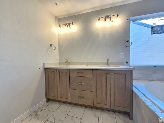 Bathroom with marble finish flooring, a relaxing tiled tub, and double vanity | Image 18