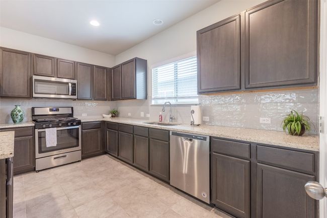 Kitchen featuring a sink, tasteful backsplash, appliances with stainless steel finishes, and dark brown cabinets | Image 17