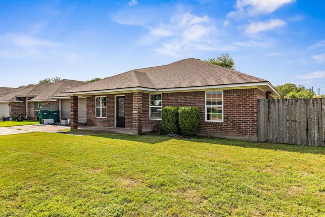 Ranch-style home featuring brick siding, concrete driveway, roof with shingles, a patio, and a garage | Image 6