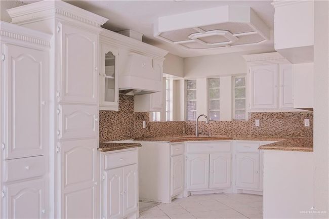 Kitchen featuring dark stone countertops, tasteful backsplash, white cabinetry, and a sink | Image 10