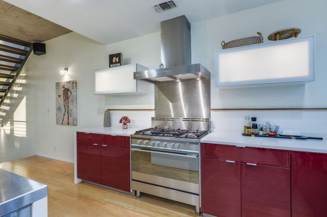 Kitchen featuring light hardwood / wood-style flooring, stainless steel counters, decorative backsplash, gas range, and wall chimney exhaust hood | Image 16