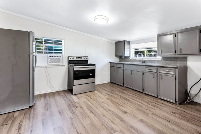 Kitchen featuring stainless steel appliances, gray cabinets, light wood-style flooring, crown molding, and backsplash | Image 20