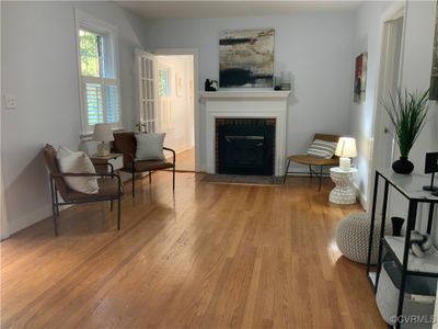 Living room with a wood fireplace and light hard wood flooring | Image 3