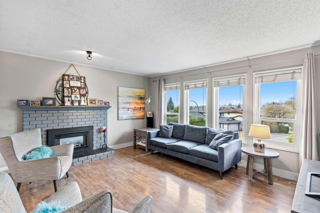 Living area with baseboards, a textured ceiling, crown molding, a fireplace, and wood finished floors | Image 8